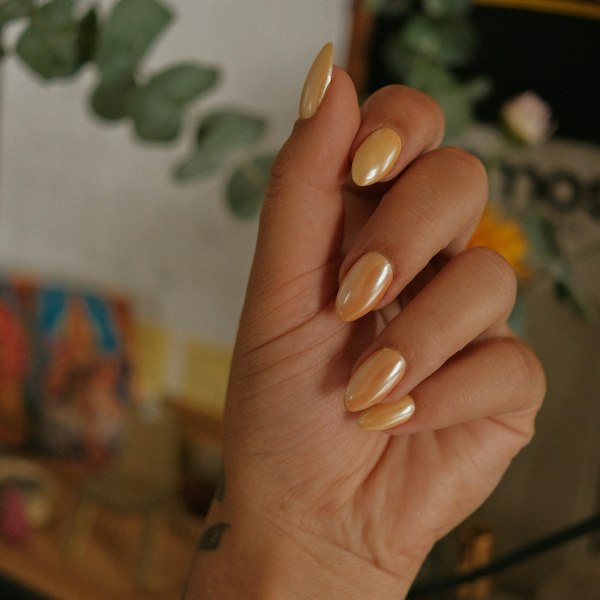 Hand with glossy golden almond nails