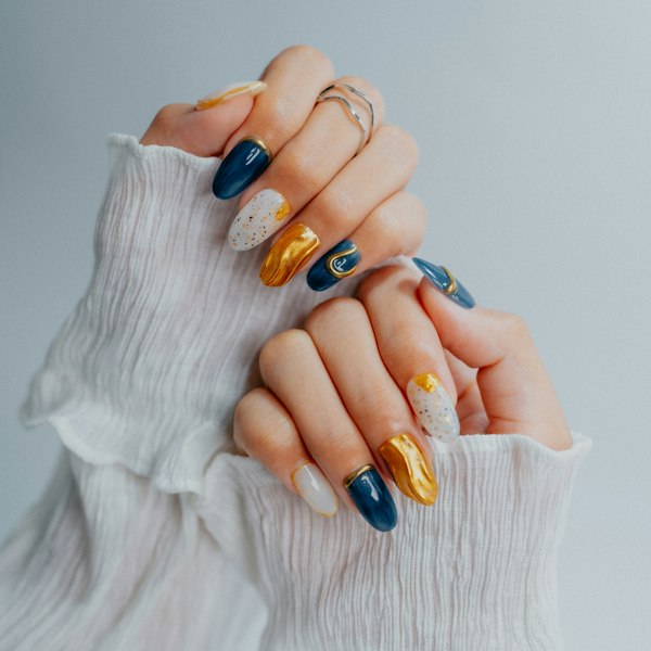 Hands with navy, gold and white nail designs
